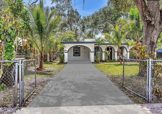 ranch-style home featuring concrete driveway, fence, a gate, and stucco siding