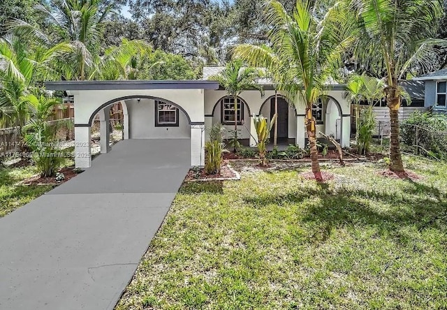 view of front of home featuring a carport, fence, concrete driveway, a front lawn, and stucco siding