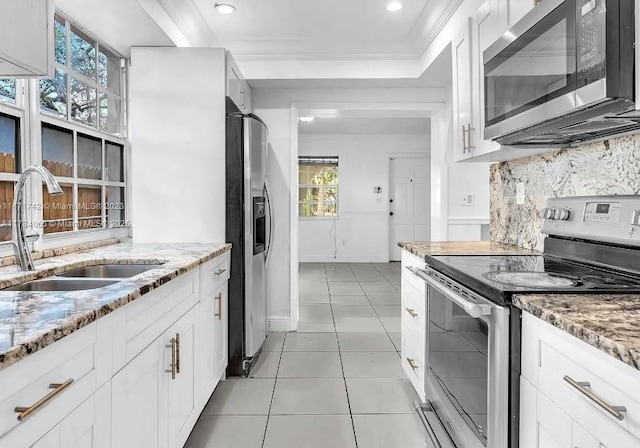 kitchen with stainless steel appliances, a sink, ornamental molding, and light tile patterned flooring