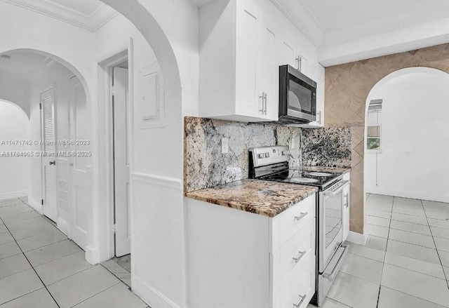 kitchen featuring stainless steel appliances, light tile patterned floors, white cabinets, and ornamental molding