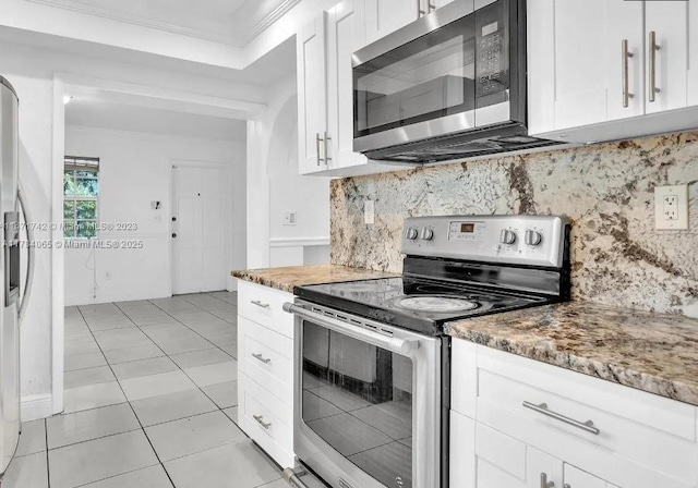 kitchen with ornamental molding, light tile patterned floors, white cabinetry, decorative backsplash, and appliances with stainless steel finishes