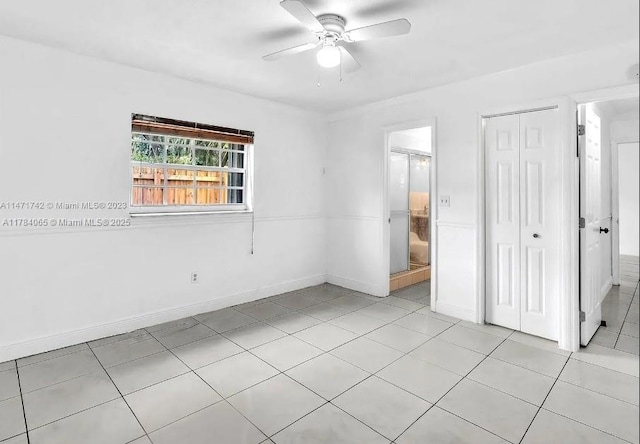 unfurnished bedroom with a closet, baseboards, ceiling fan, and connected bathroom