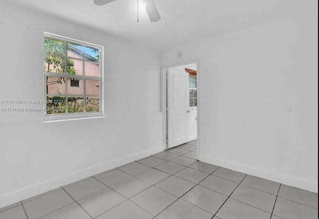 empty room with ceiling fan, baseboards, and light tile patterned floors