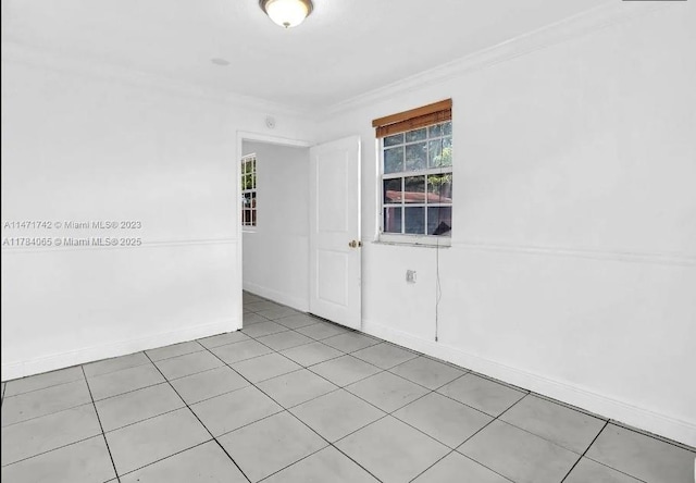 spare room with crown molding, baseboards, and light tile patterned flooring