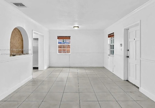 spare room featuring visible vents, baseboards, crown molding, and light tile patterned flooring