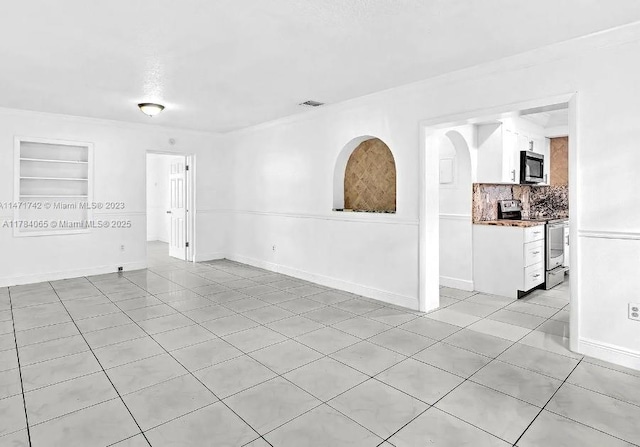 empty room featuring visible vents, built in shelves, light tile patterned floors, and baseboards