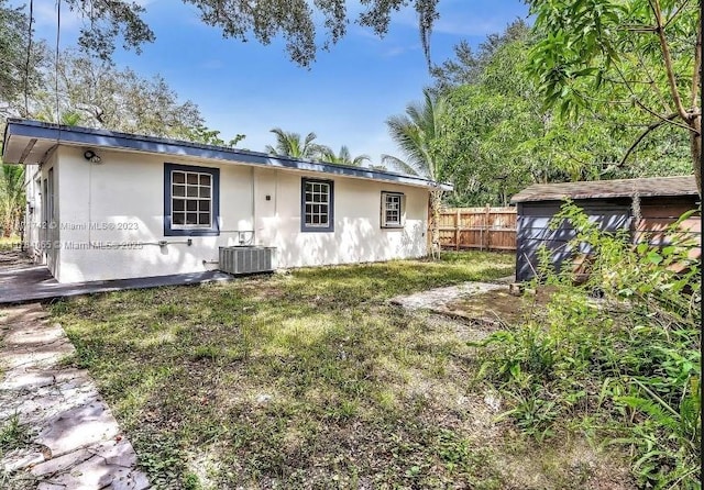 back of property featuring central air condition unit, stucco siding, and fence