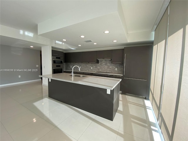 kitchen featuring light countertops, stovetop, a sink, and backsplash
