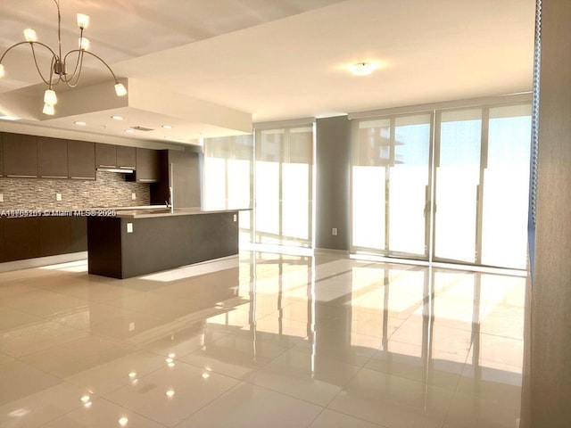 kitchen with tasteful backsplash, light tile patterned floors, light countertops, a kitchen island with sink, and modern cabinets