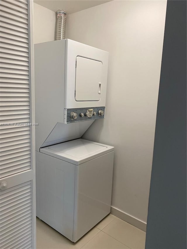 laundry room with laundry area, light tile patterned floors, baseboards, and stacked washer / drying machine