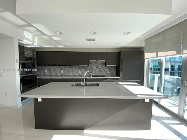 kitchen with visible vents, light countertops, a sink, stainless steel double oven, and backsplash