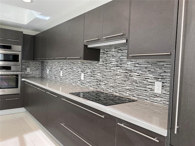 kitchen with under cabinet range hood, decorative backsplash, light countertops, and stainless steel double oven