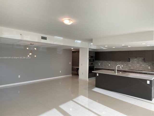kitchen with tasteful backsplash, light countertops, light tile patterned flooring, visible vents, and a sink