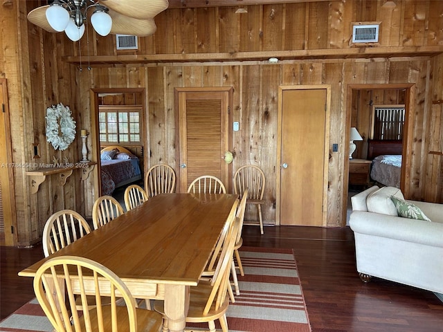 dining area with ceiling fan, wood walls, and visible vents