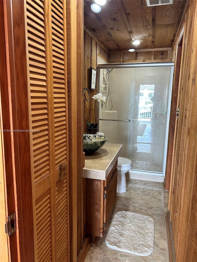 bathroom featuring stone finish floor, a shower stall, vanity, wooden ceiling, and toilet