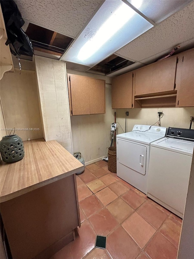 clothes washing area featuring cabinet space, light tile patterned floors, and washer and dryer