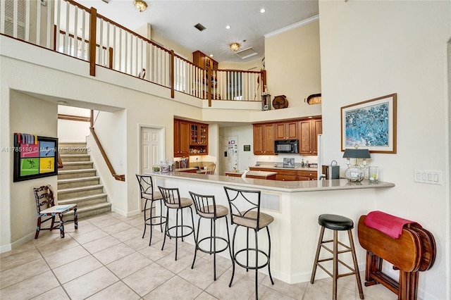 1951 NW 167th Ter, Pembroke Pines, FL 33028 - kitchen with brown cabinets, black microwave, a high ceiling, a kitchen bar, and a peninsula