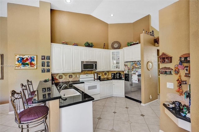 11257 NW 51st St, Coral Springs, FL 33076 - kitchen featuring high vaulted ceiling, a kitchen breakfast bar, a peninsula, dark countertops, and stainless steel appliances