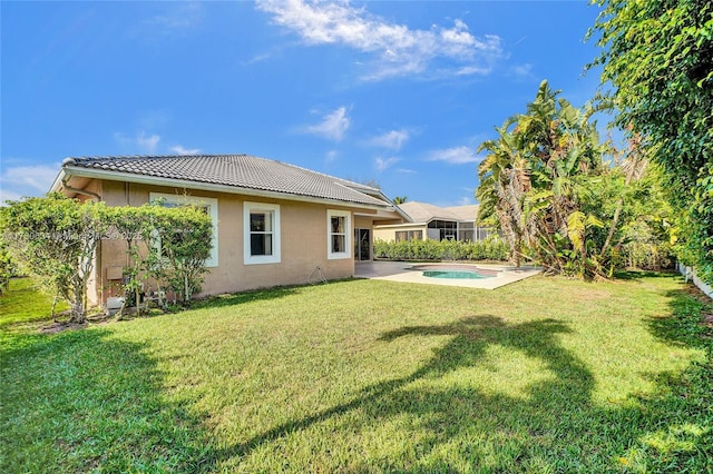 11257 NW 51st St, Coral Springs, FL 33076 - rear view of property featuring a yard, a jacuzzi, a tiled roof, a patio area, and stucco siding