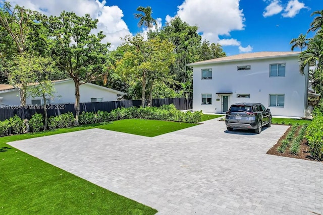 view of front facade featuring a front yard, stucco siding, and fence