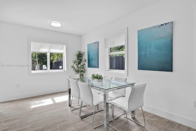dining space featuring light wood-style flooring, plenty of natural light, and baseboards