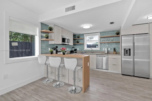 kitchen featuring open shelves, white cabinetry, appliances with stainless steel finishes, light countertops, and backsplash