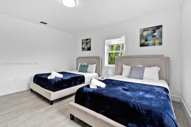 bedroom featuring visible vents, baseboards, and wood finished floors