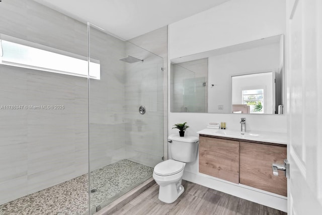 bathroom featuring a shower stall, wood finished floors, vanity, and toilet