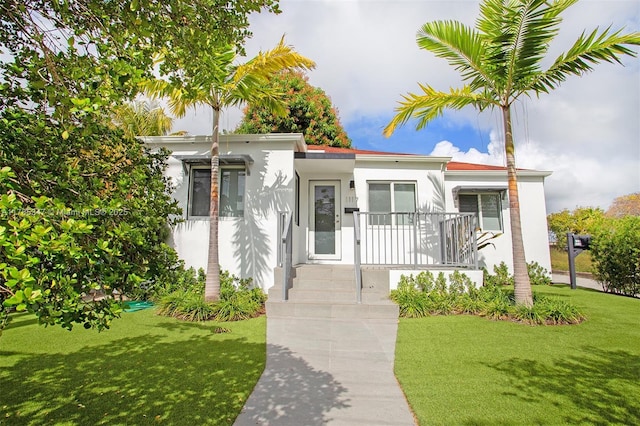 bungalow featuring stucco siding and a front yard