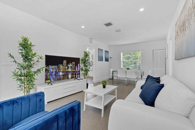 living room with visible vents, baseboards, recessed lighting, and finished concrete floors