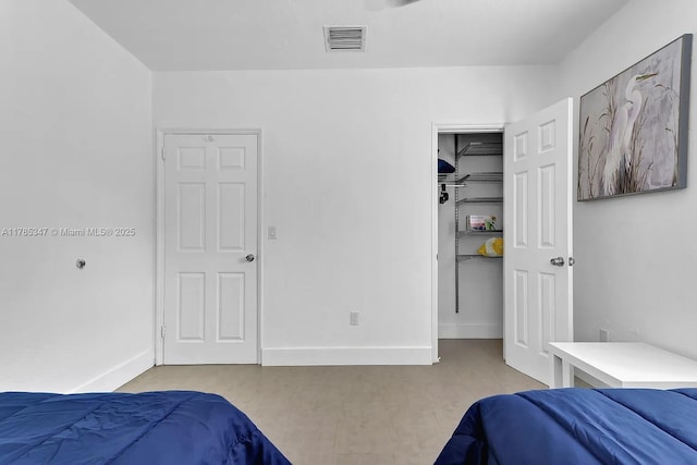 bedroom with a walk in closet, a closet, baseboards, and visible vents