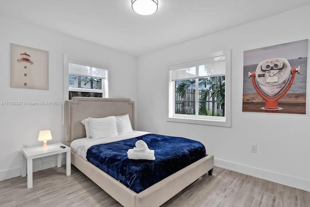 bedroom with wood finished floors, baseboards, and multiple windows