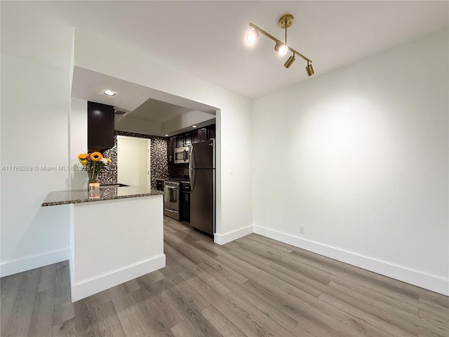 1601 S Flagler Dr Unit 211O, West Palm Beach, FL 33401 - kitchen featuring dark stone countertops, wood finished floors, backsplash, baseboards, and appliances with stainless steel finishes