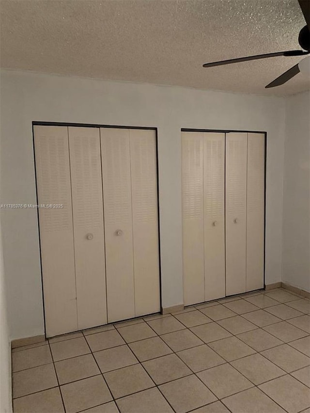 1810 W 56th St Unit 3127, Hialeah, FL 33012 - unfurnished bedroom with a textured ceiling, light tile patterned flooring, two closets, and ceiling fan