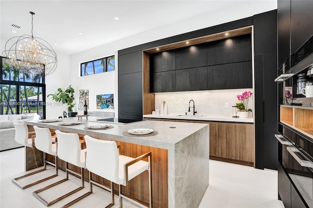 kitchen with dark cabinetry, wall oven, modern cabinets, and a sink