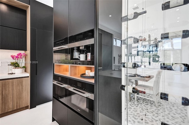kitchen featuring visible vents, modern cabinets, wall oven, and dark cabinets