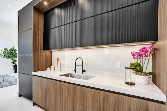 kitchen featuring tasteful backsplash, modern cabinets, light countertops, and a sink