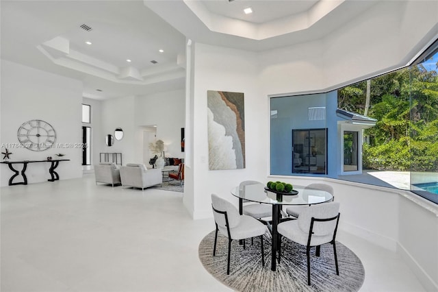 dining room featuring visible vents, plenty of natural light, a tray ceiling, and a high ceiling