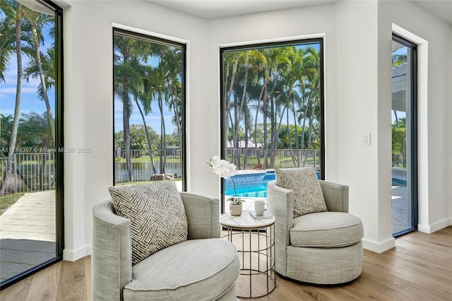 living area with baseboards, wood finished floors, and a water view
