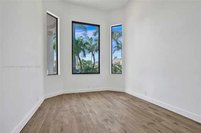 spare room featuring baseboards and wood finished floors