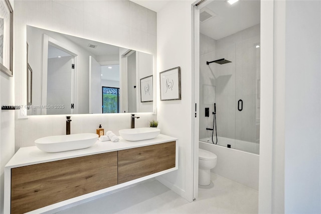 bathroom with toilet, double vanity, a sink, and enclosed tub / shower combo