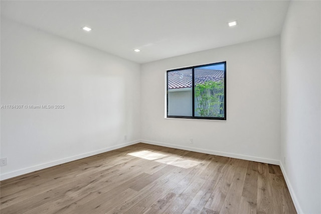 spare room featuring hardwood / wood-style flooring, recessed lighting, and baseboards
