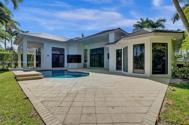 back of property featuring a patio, an outdoor pool, stucco siding, and a tiled roof