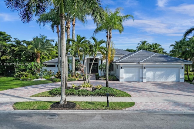 view of front of house with stucco siding, decorative driveway, and an attached garage