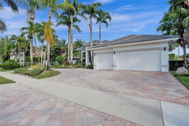 view of front of property with a tile roof, decorative driveway, stucco siding, and a garage