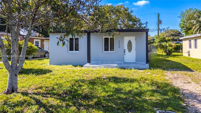 bungalow-style house with stucco siding and a front yard