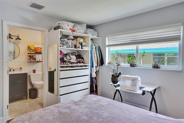 bedroom with ensuite bathroom, visible vents, and a sink