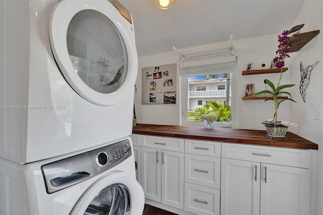 clothes washing area featuring cabinet space and stacked washer / drying machine