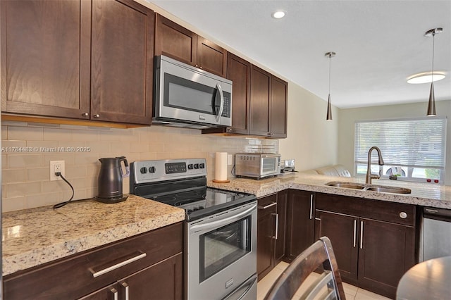 kitchen with tasteful backsplash, dark brown cabinetry, light stone countertops, stainless steel appliances, and a sink
