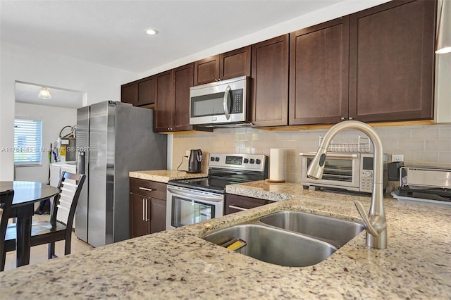 kitchen featuring decorative backsplash, a sink, dark brown cabinetry, and appliances with stainless steel finishes